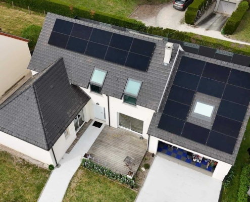 Vue de panneaux photovoltaïques installés sur deux parties d'une toiture sur la maison d'un particulier.